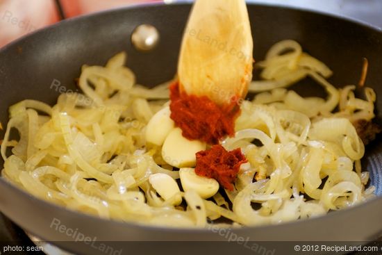 Add the tomato paste, garlic cloves