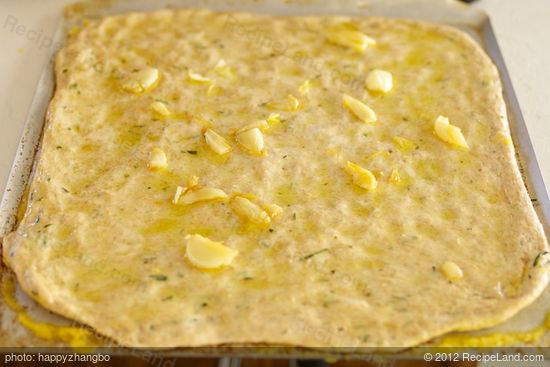 Brush garlic infused oil over surface of each focaccia, dividing evenly.  