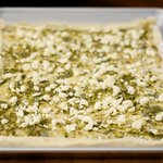 Sprinkle about half of the crumbled feta cheese over the pesto layer.