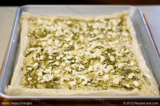 Sprinkle about half of the crumbled feta cheese over the pesto layer.