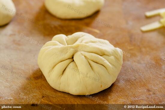 and pinch together the edges of the dough to seal and form the stuffed bun.