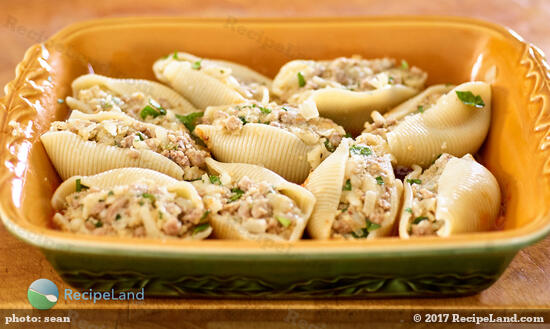 Pasta shells stuffed with beef in casserole dish, ready for the sauce