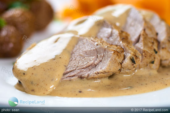 Close-up of juicy pork tenderloin with spoonful of mustard white wine sauce