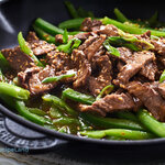 Quick, easy marinated ginger beef strips. Asian inspired steak strips glazed in a ginger honey soy sauce with green peppers served over rice.
