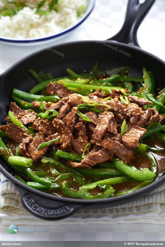 Quick, easy marinated ginger beef strips. Asian inspired steak strips glazed in a ginger honey soy sauce with green peppers served over rice.
