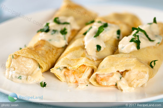Seafood crepes with garlic cream cheese sauce on a plate.