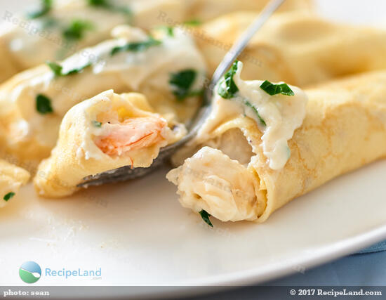 Close-up of seafood crepes with shrimp and scallops in garlic sauce