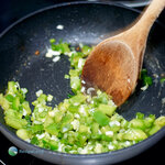Stirring diced green bell pepper and scallions to combine