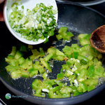 Adding scallions to a skillet of green bell pepper.