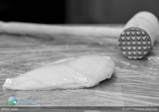 Chicken breast on cutting board with meat mallet