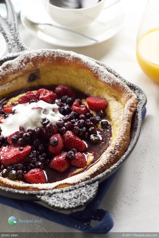 An impressive yet easy to make baked breakfast pancake that achieves a massive height and is filled with berries and yogurt.