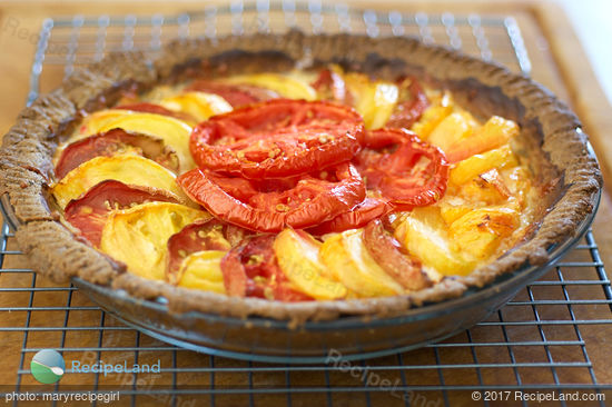 The herbed tomato pie after first baking, removed from the oven on a wire rack ready for drizzling of herbed oil topping.