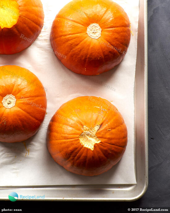 Halved sugar pumpkins, cut side down on a rimmed baking sheet lined with parchment paper.