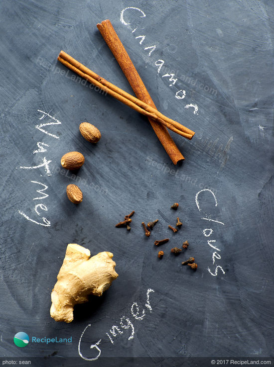 Raw ingredients for Pumpkin Pie Spice mix arranged on a black chalkboard background