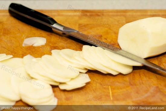 While the sauce is simmering, peel and thinly slice the potatoes...