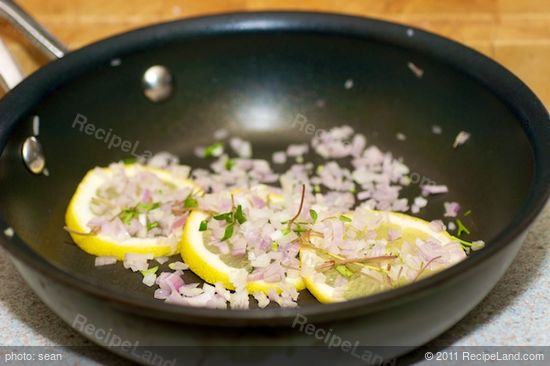 Arrange lemon slices, shallots and herbs in the pan