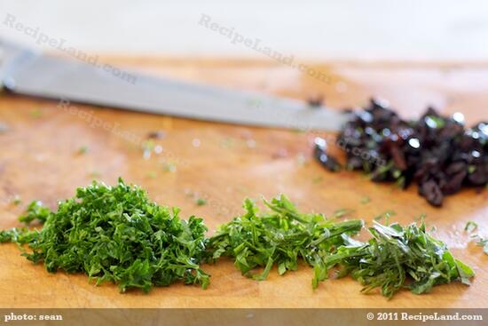 Mince the herbs, pit and chop the olives.