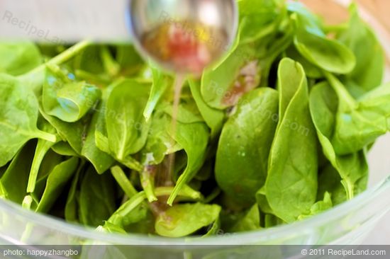 In a large bowl, add spinach and 2 tablespoons of vinaigrette.