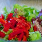 Add the sliced roasted bell pepper into the prepare mixed green salad. 