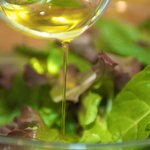 Drizzle the olive oil over the mixed greens in a large bowl.