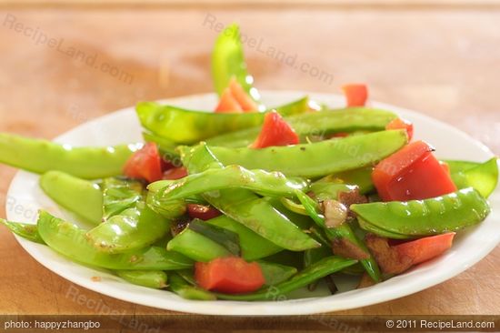 Add the snow peas, red bell pepper and garlic to a hot skillet with 1 tablespoon of vegetable oil added,