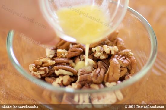 In a medium bowl, pour the melted butter into the coarsely chopped pecans.
