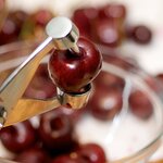 Using a cherry pitter removes the seed over a bowl to catch all the juice.