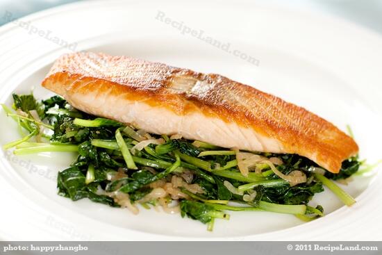 Divide the cooked baby spinach or tatsoi evenly among 4 serving plates. 