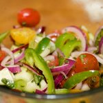 Add the tomatoes, cucumber, onion, peppers, olives and feta cheese into the bowl with the dressing, toss until well coated and distributed.    