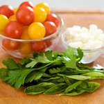 Then finely chop the fresh herbs, half the cherry tomatoes and crumble the cheese, and set aside.