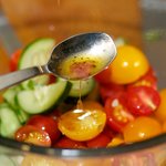 Add both tomatoes and cucumbers into a medium bowl, drizzle with half vinaigrette.