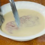 With a tongs, dip the chop into the milk mixture,