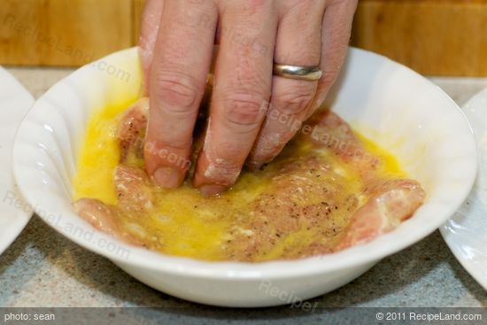 Using tongs dip in the egg wash.