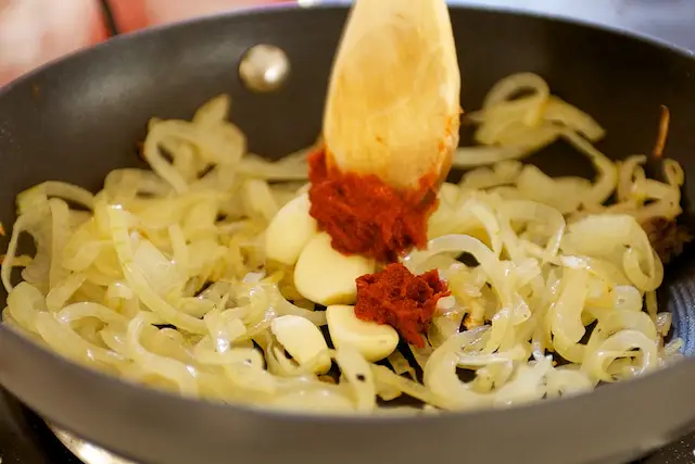 Add the tomato paste, garlic cloves