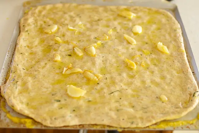 Brush garlic infused oil over surface of each focaccia, dividing evenly.  