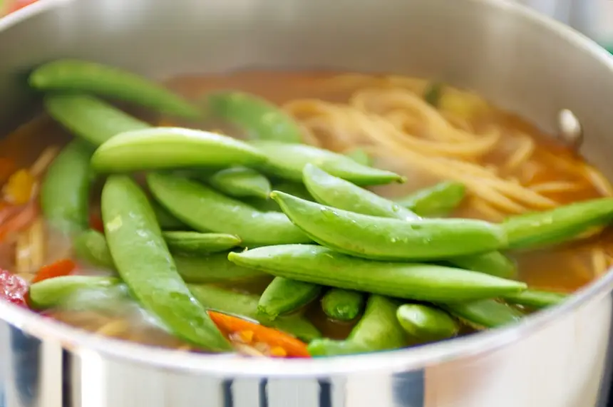 sugar snap peas, scallions, and half of the cilantro into the pot.