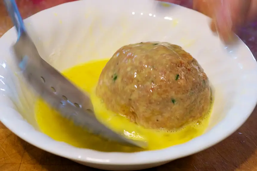 Transfer floured egg into beaten egg.