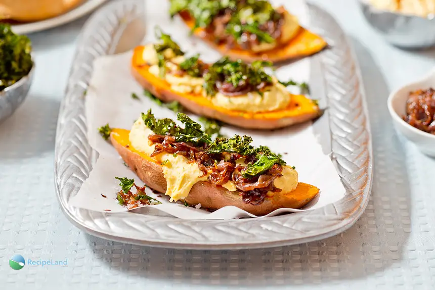 Sweet potatoes topped with caramelized onions, hummus and crispy kale chips