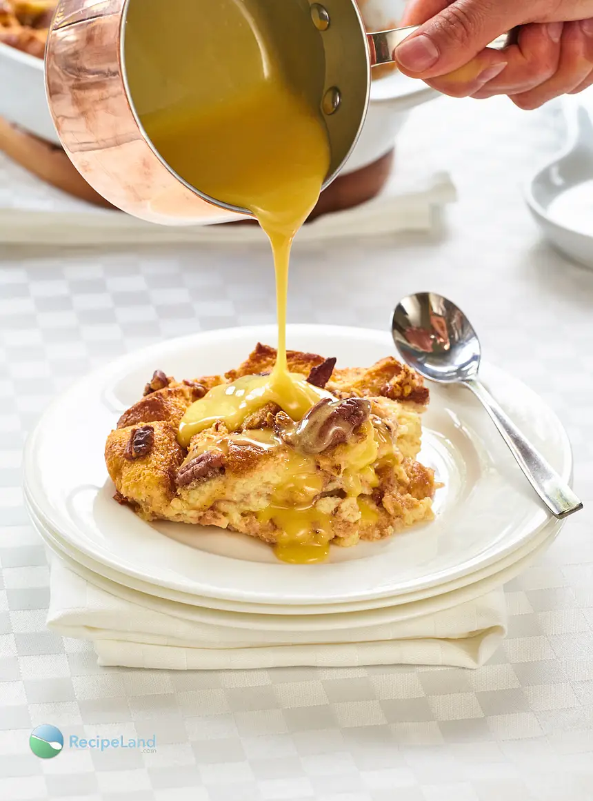 Pouring whiskey sauce for bread pudding over a serving of Lazarus bread pudding.
