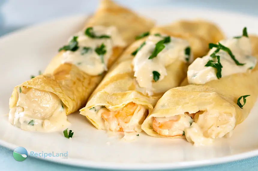 Seafood crepes with garlic cream cheese sauce on a plate.