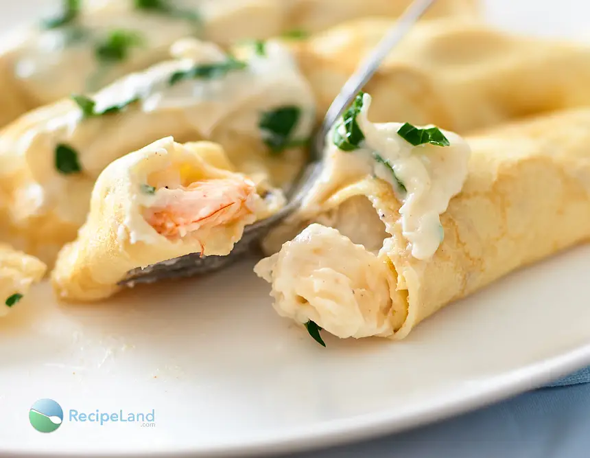 Close-up of seafood crepes with shrimp and scallops in garlic sauce