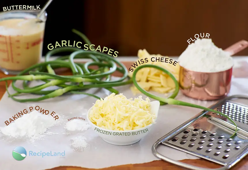 Ingredients to make garlic scape cheese biscuits on a wood cutting board