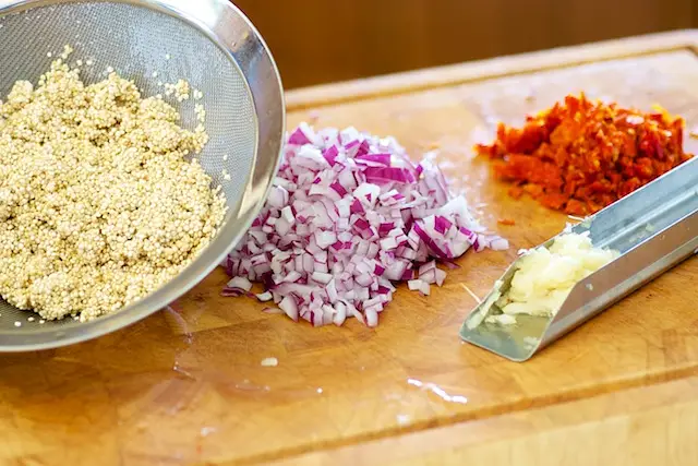 Rinse the quinoa and chop the onion, sun-dried tomatoes and garlic