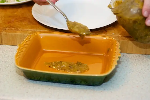Spoon some of the enchilada sauce into the <a href="/how-to/baking-pan-and-dish-volume-guide" title="Baking Pan and Dish Volume Guide">baking dish</a> 