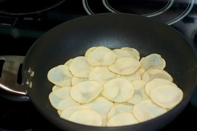 Add the <a href="/how-to/how-to-store-potatoes" title="How to store potatoes">potatoes</a> to the pan and cook