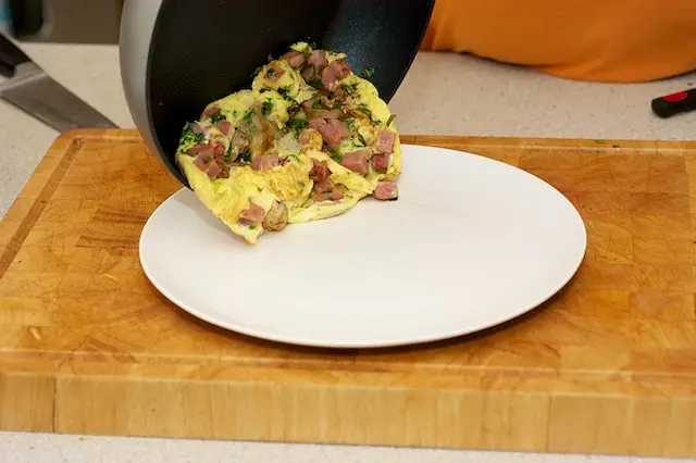 Edge of the pan on the plate and beginning the flip