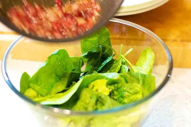 Pour the dressing over the spinach...