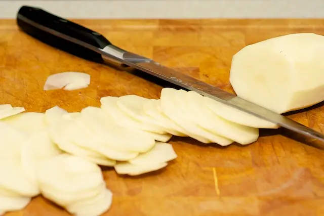 While the sauce is simmering, peel and thinly slice the potatoes...