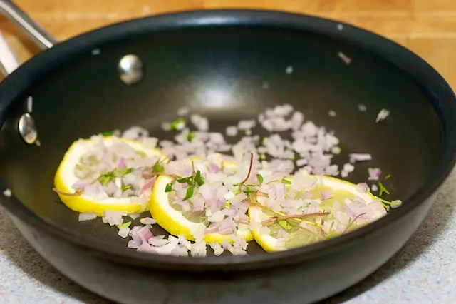 Arrange lemon slices, shallots and herbs in the pan