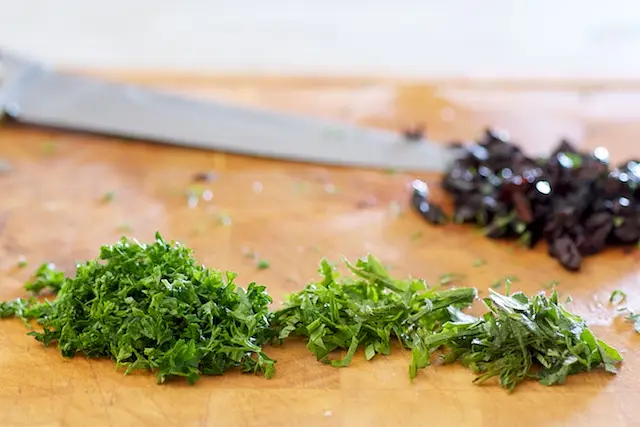 Mince the herbs, pit and chop the olives.